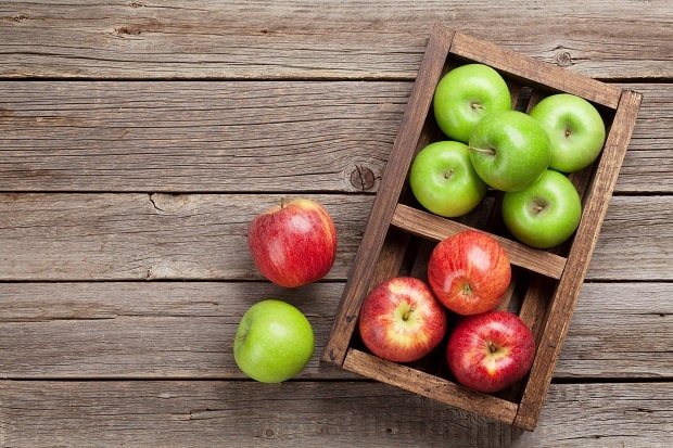 червени и зелени ябълки в дървена кутия